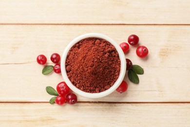 Photo of Dried cranberry powder in bowl, fresh berries and green leaves on light wooden table, top view