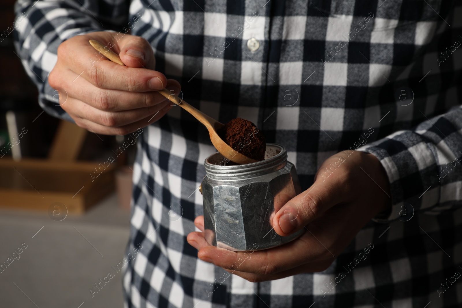 Photo of Man putting ground coffee into moka pot indoors, closeup
