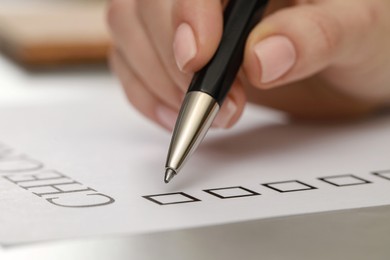 Photo of Woman filling Checklist at light grey table, closeup