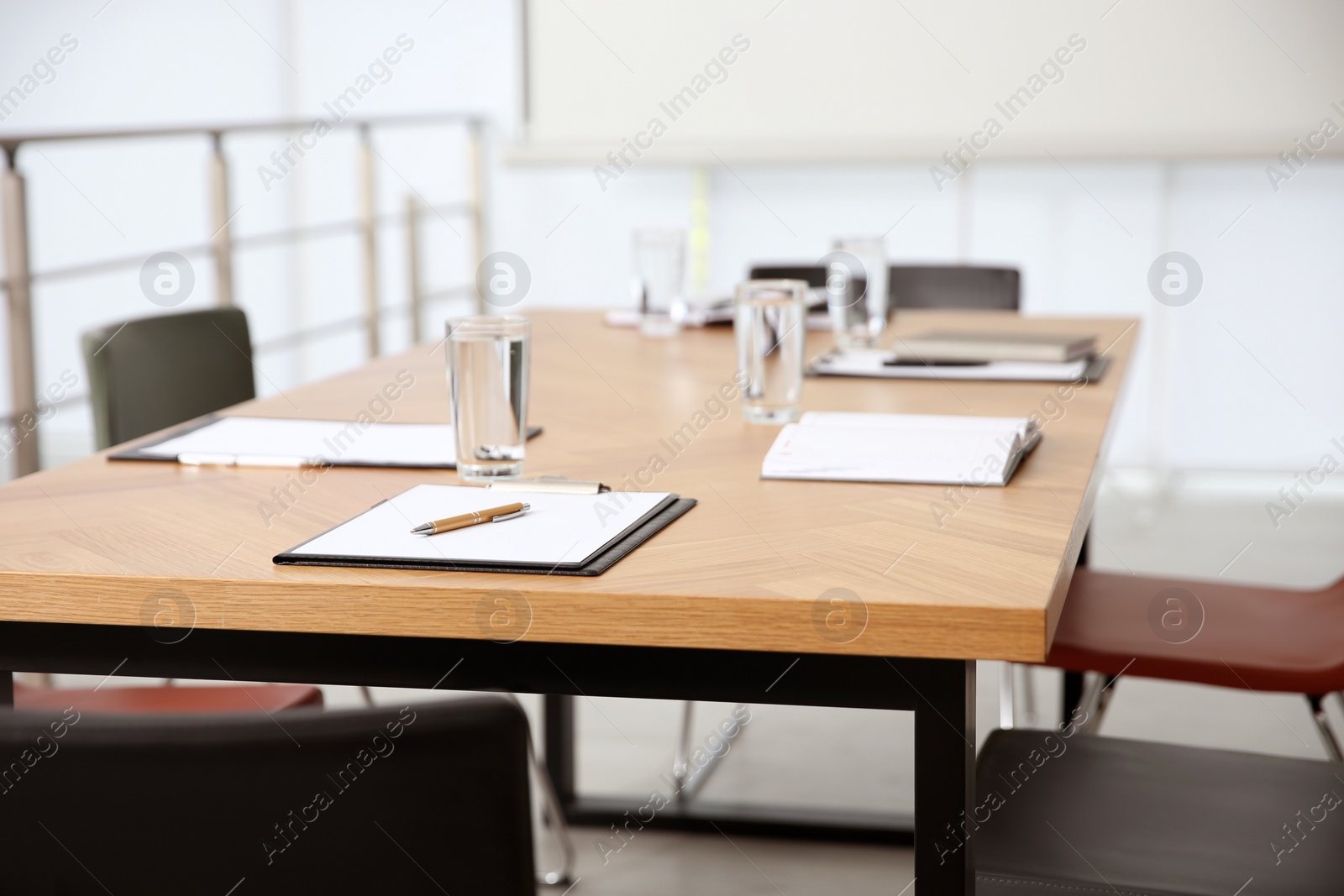 Photo of Clipboards and glasses of water on wooden table in modern office