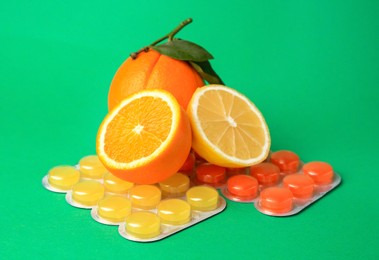 Blisters with cough drops and fresh fruits on green background