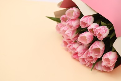 Photo of Beautiful bouquet of fresh pink tulips on beige background. Space for text