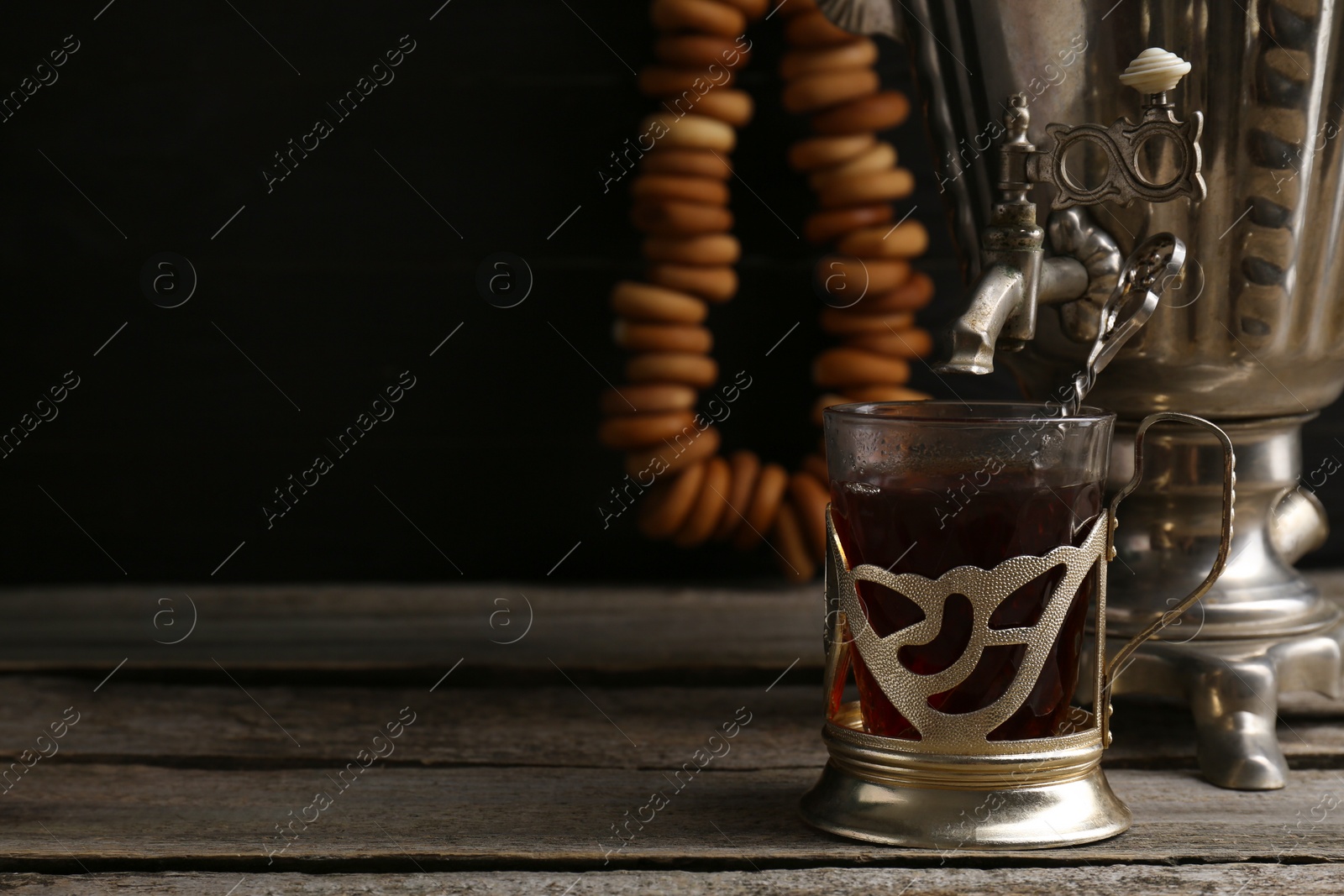 Photo of Delicious tea and ring shaped Sushki (dry bagels), focus on cup with samovar. Space for text