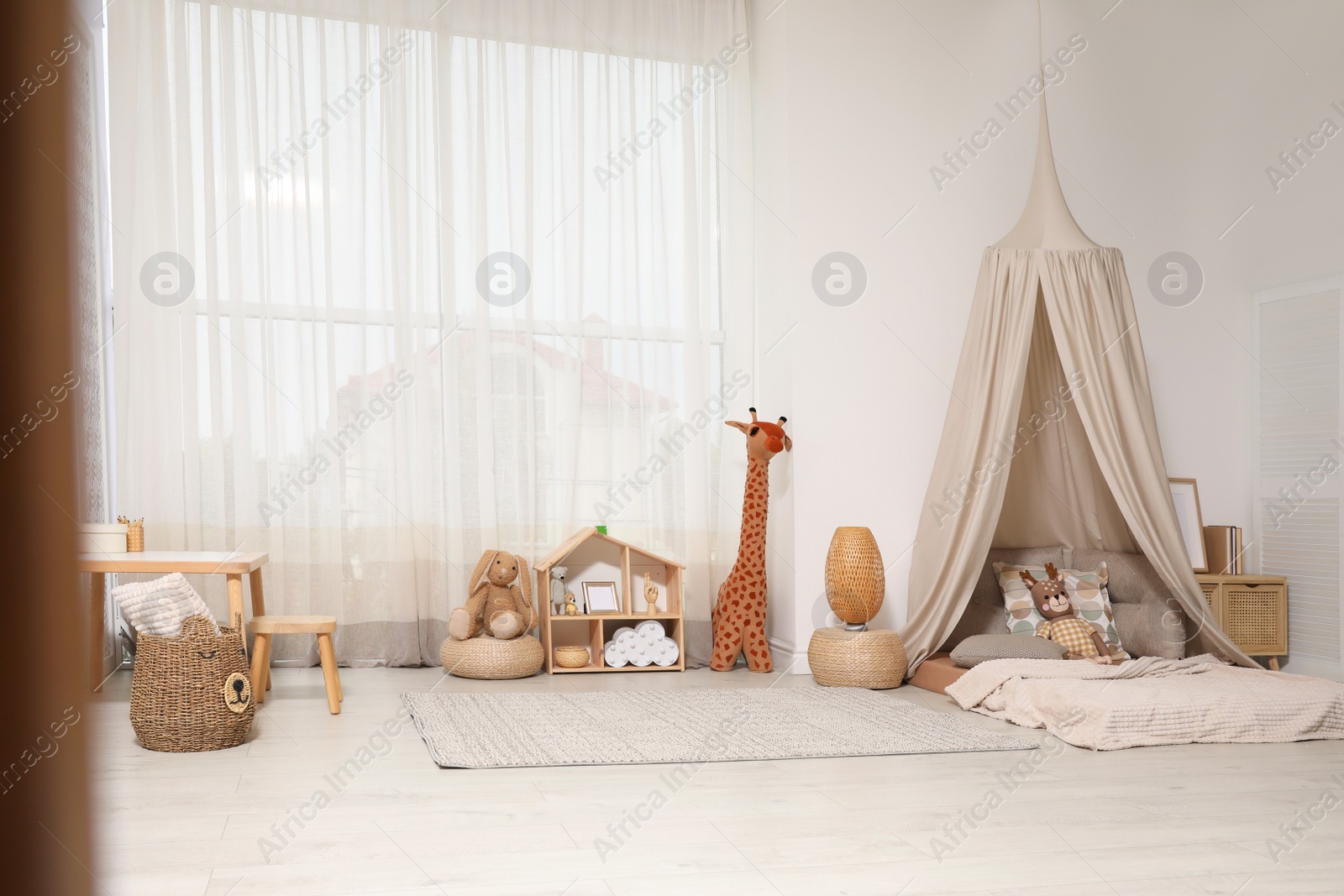 Photo of Cozy kids room with play tent, toys and comfortable floor bed. Montessori interior