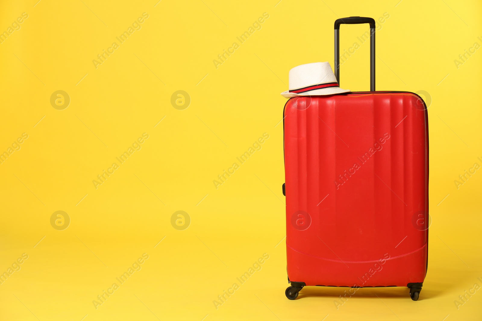 Photo of Bright suitcase with hat on color background. Space for text