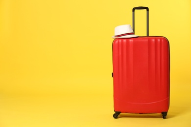 Photo of Bright suitcase with hat on color background. Space for text
