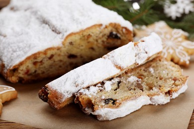 Traditional Christmas Stollen with icing sugar on wooden board, closeup