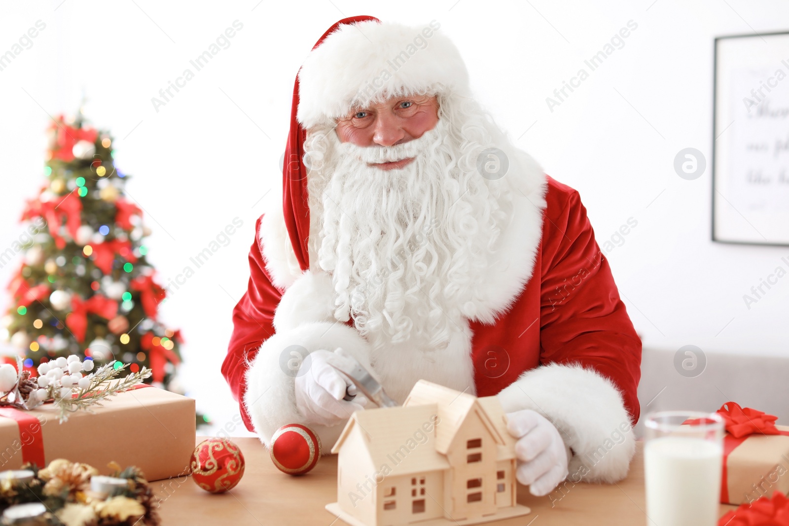 Photo of Authentic Santa Claus making toy at table in workshop