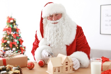 Authentic Santa Claus making toy at table in workshop