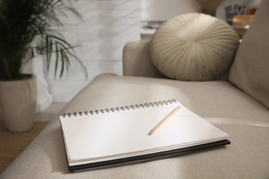 Notebook and pencil on light grey sofa in living room