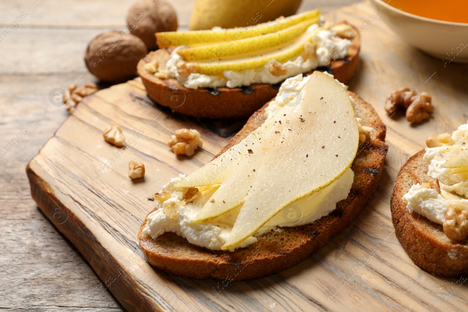 Photo of Toasted bread with tasty cream cheese and pear on wooden board