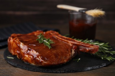 Tasty marinated meat and rosemary on wooden table, closeup