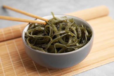 Photo of Tasty seaweed salad in bowl served on gray table, closeup