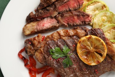 Photo of Delicious grilled beef steak and vegetables on plate, top view
