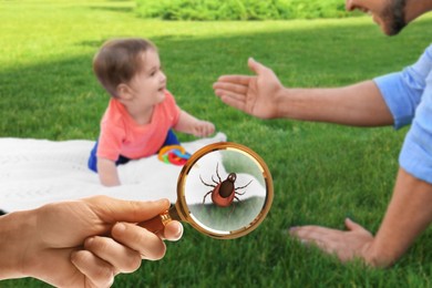 Image of Seasonal hazard of outdoor recreation. Little baby crawling towards father on blanket in nature. Woman showing tick with magnifying glass, selective focus