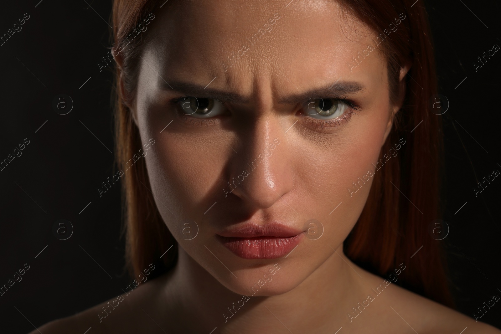 Photo of Evil eye. Young woman with scary eyes on black background, closeup