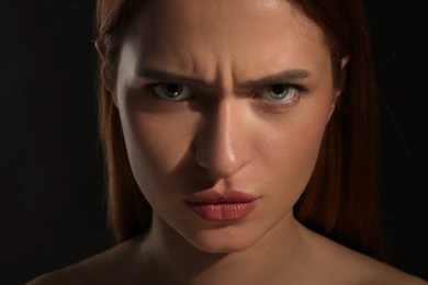 Photo of Evil eye. Young woman with scary eyes on black background, closeup
