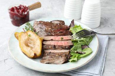 Photo of Delicious roasted beef meat, caramelized pear and greens served on light table, closeup