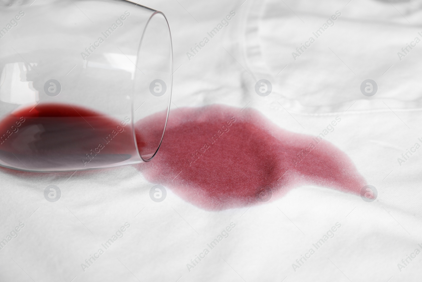 Photo of Overturned glass and spilled exquisite red wine on white t-shirt. Space for text