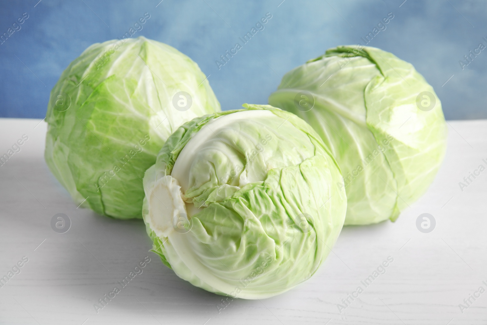 Photo of Whole cabbages on white table. Healthy food