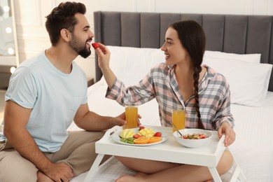 Happy couple having breakfast on bed at home