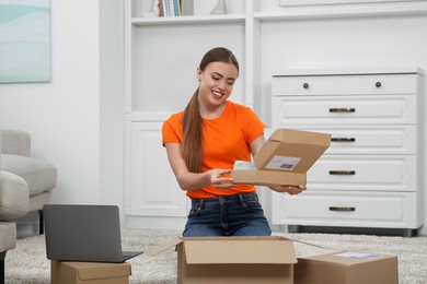 Photo of Happy woman unpacking parcel at home. Online store