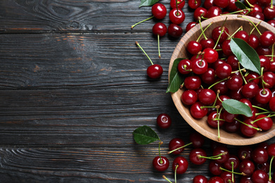 Photo of Delicious ripe sweet cherries on dark wooden table, flat lay. Space for text