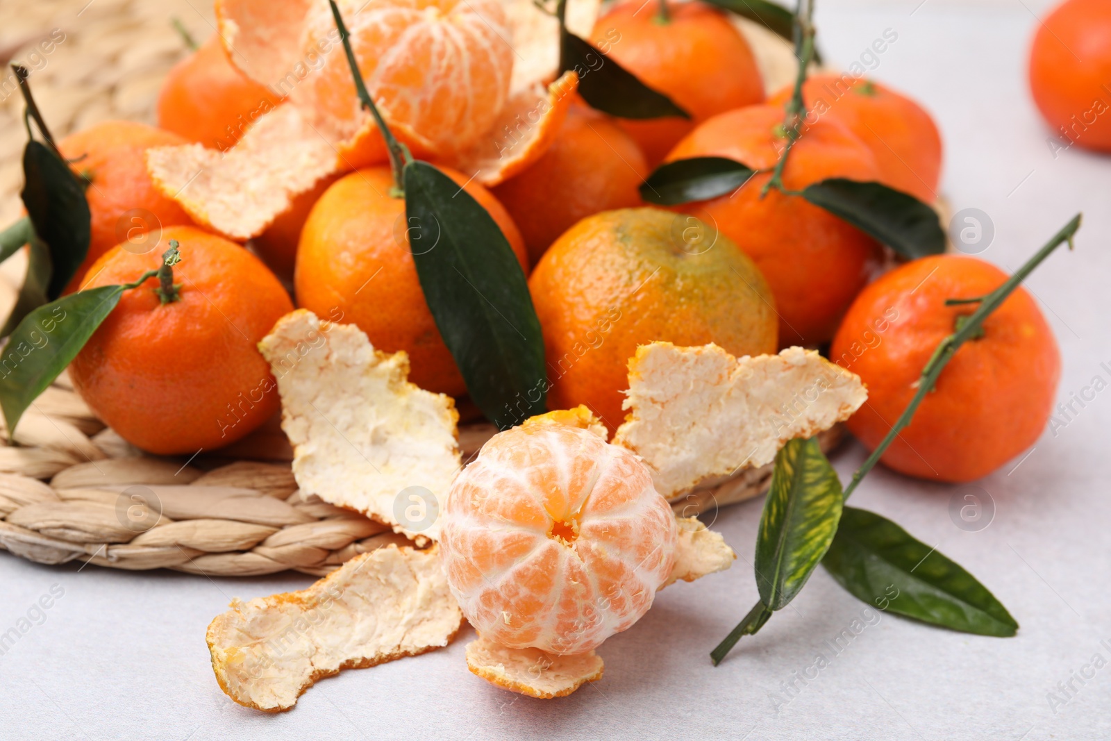 Photo of Many fresh ripe tangerines and leaves on white table