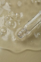 Pipette with cosmetic serum on beige background, closeup