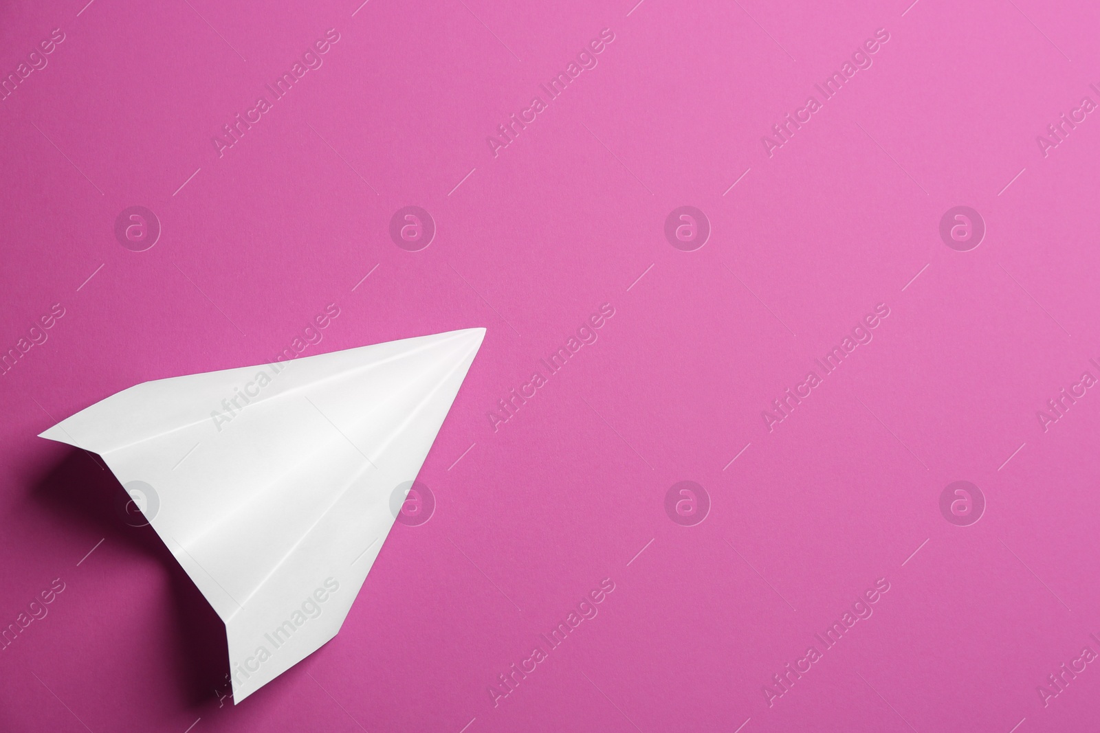 Photo of White paper plane on purple background, top view. Space for text