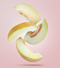 Image of Delicious ripe melon slices falling on light pink background