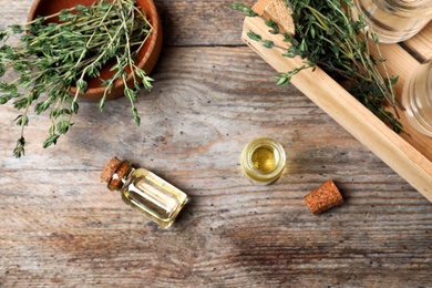 Flat lay composition with essential oil in glass bottles and thyme on wooden background