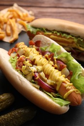 Photo of Delicious hot dogs with lettuce, onion and pickle served on table, closeup