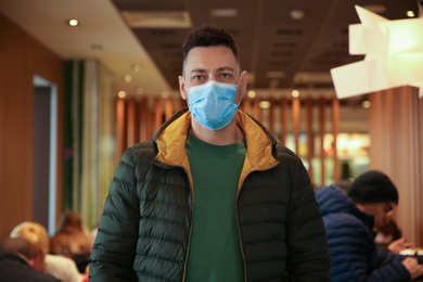 Photo of Man with disposable mask in cafe. Virus protection