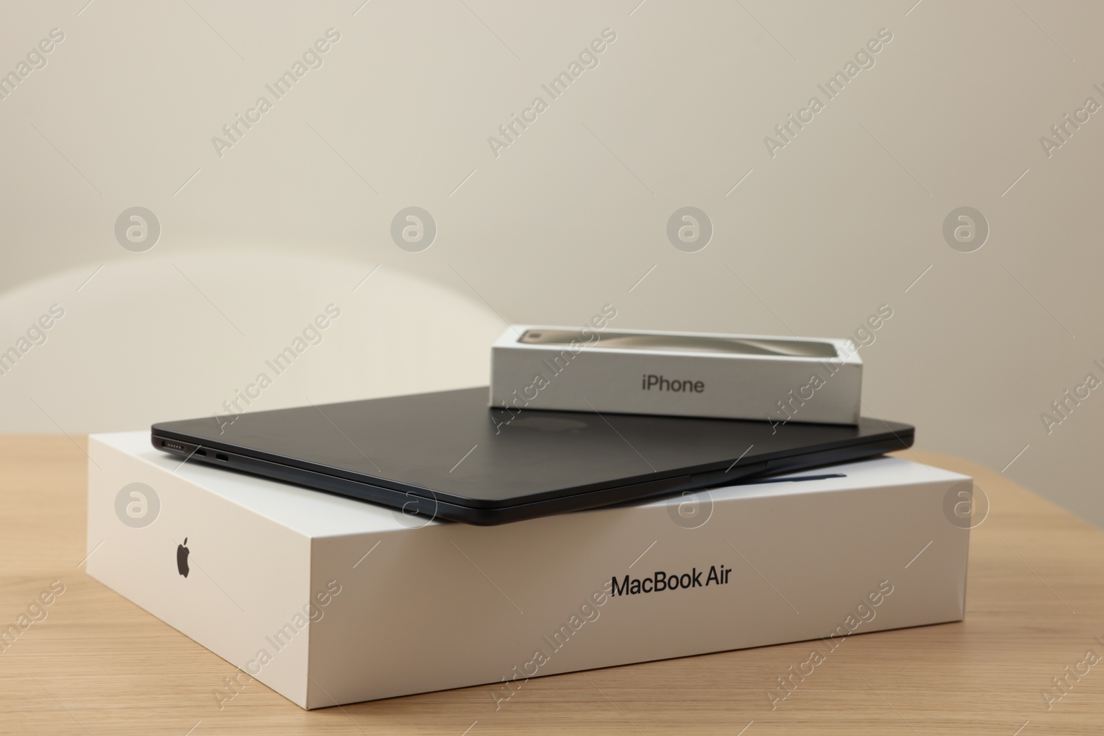 Photo of Leiden, Netherlands - October 6, 2023: Modern black MacBook Air and box from iPhone 15 Pro Max on wooden table