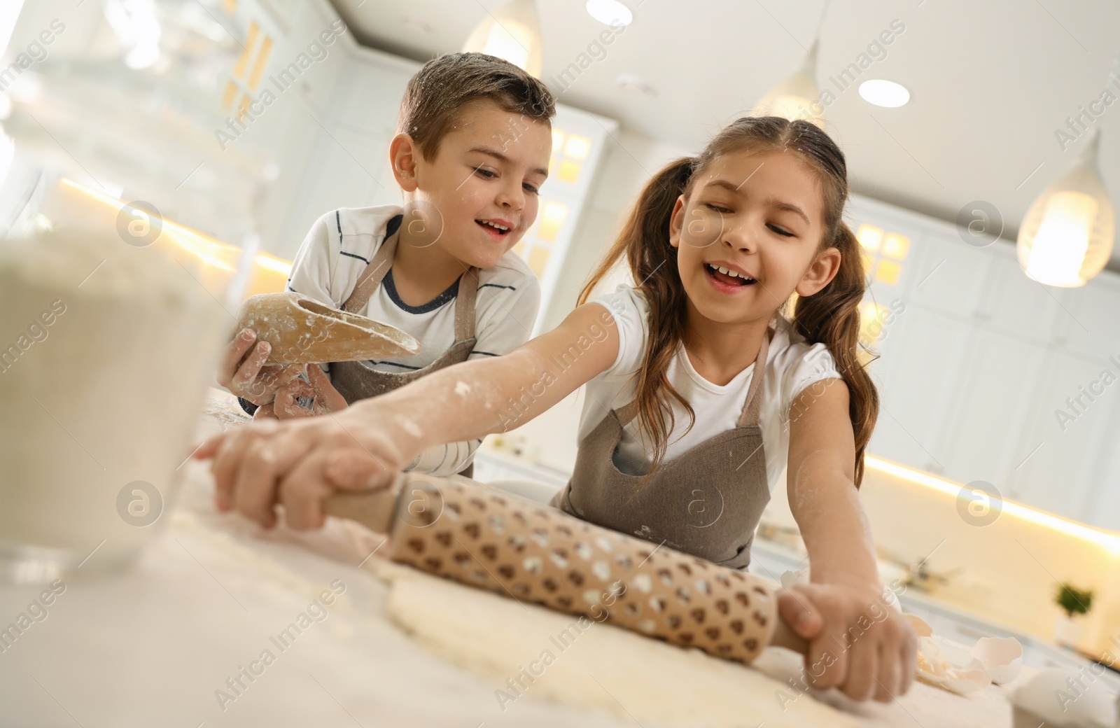 Photo of Cute little children cooking dough together in kitchen