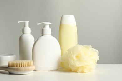 Photo of Different bath accessories on white table against grey background, closeup