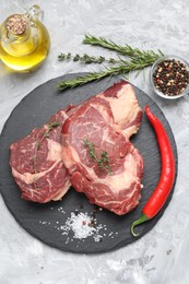 Photo of Fresh raw beef cut with different spices on light grey textured table, flat lay