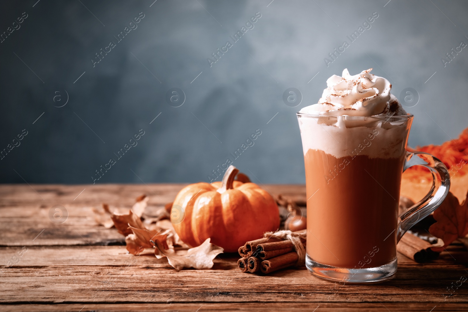 Photo of Delicious pumpkin latte and cinnamon on wooden table. Space for text