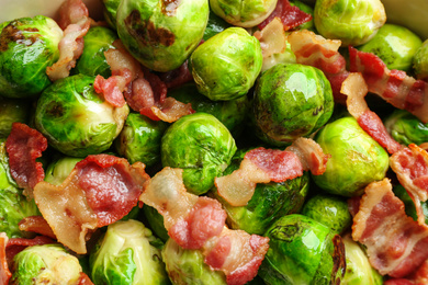 Photo of Delicious Brussels sprouts with bacon as background, top view