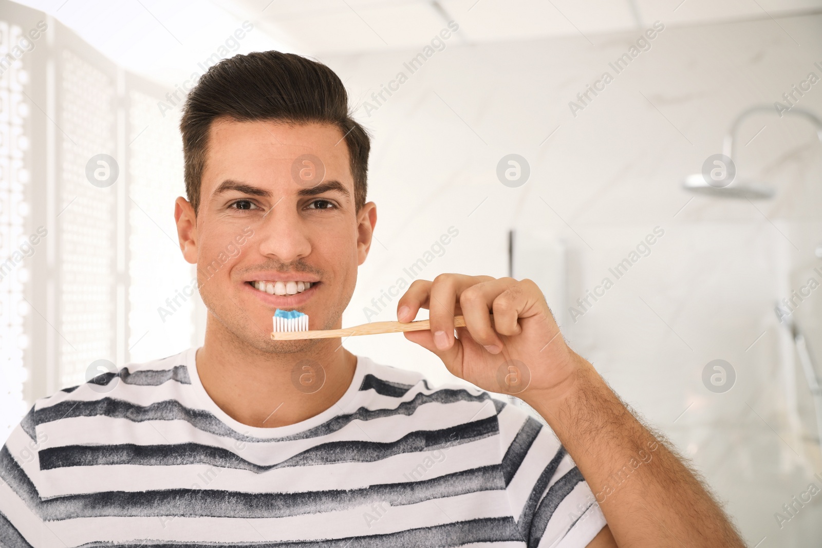 Photo of Man holding toothbrush with paste in bathroom