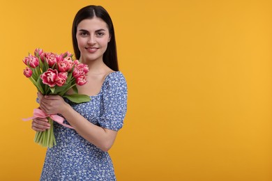 Photo of Happy young woman with beautiful bouquet on orange background. Space for text