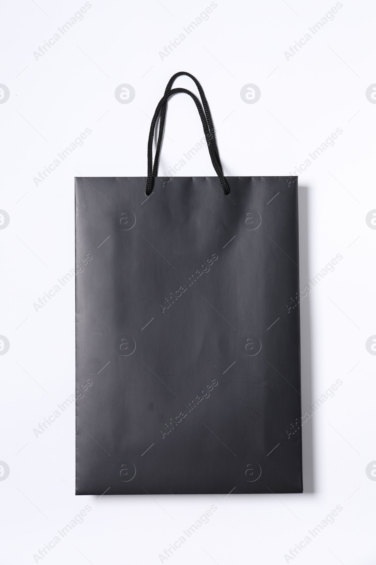 Photo of One black paper shopping bag on white background, top view