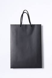 One black paper shopping bag on white background, top view