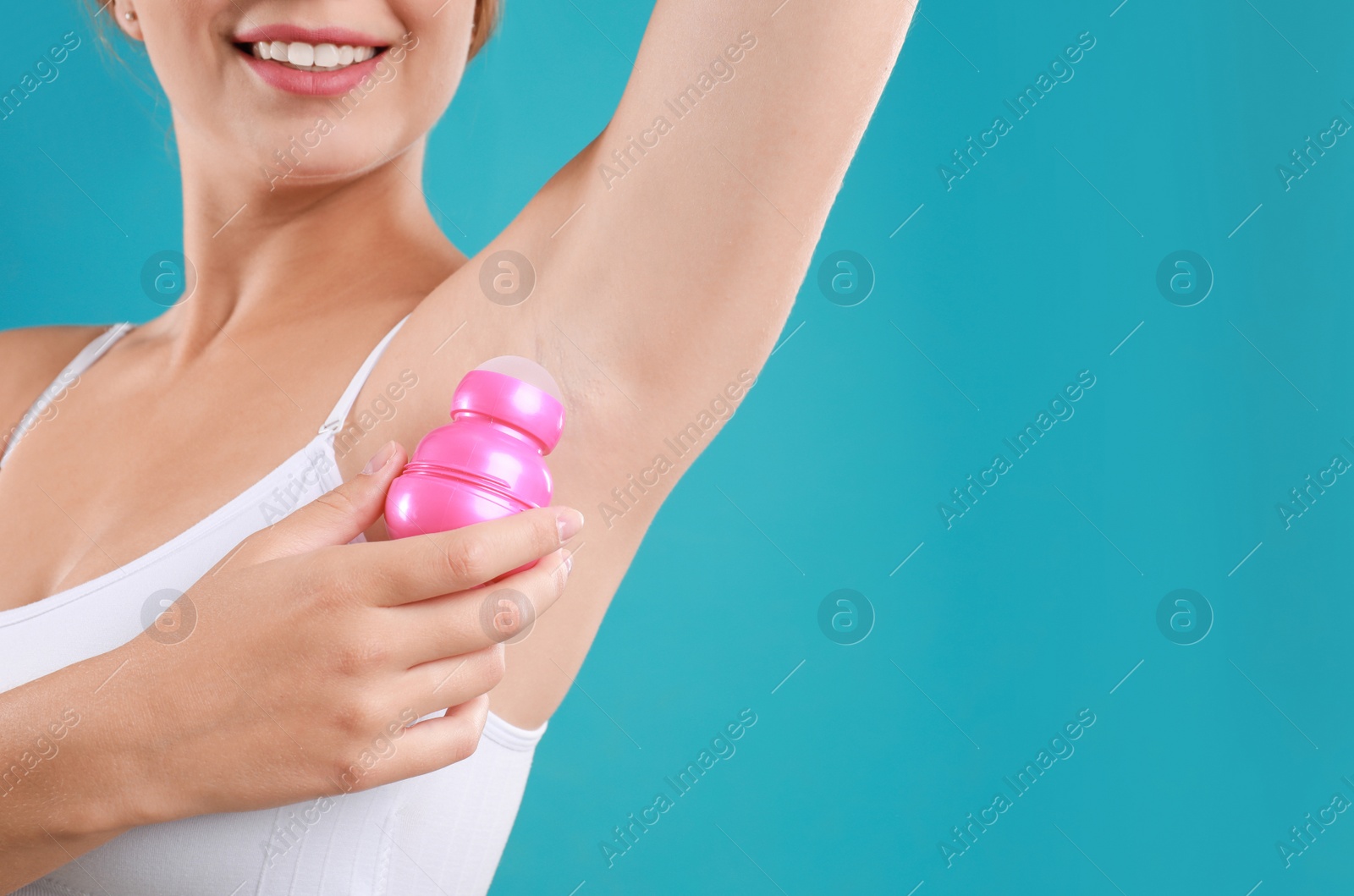 Photo of Young woman applying deodorant to armpit on teal background, closeup. Space for text