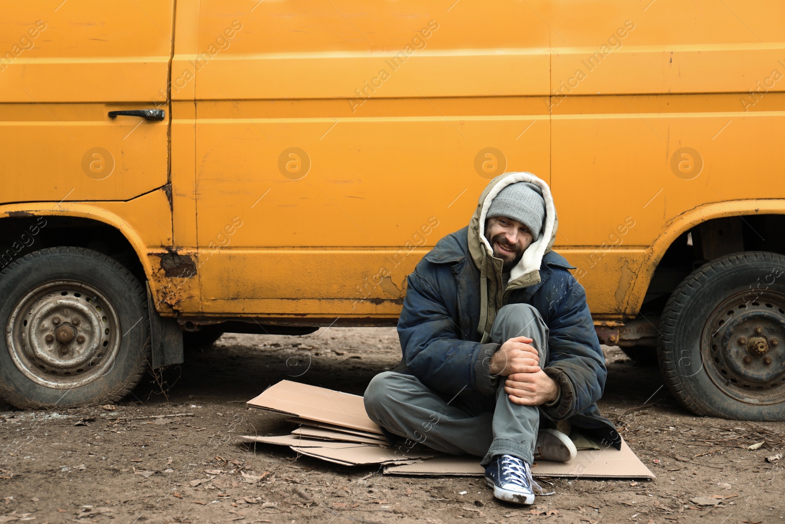 Photo of Poor homeless man sitting near van outdoors