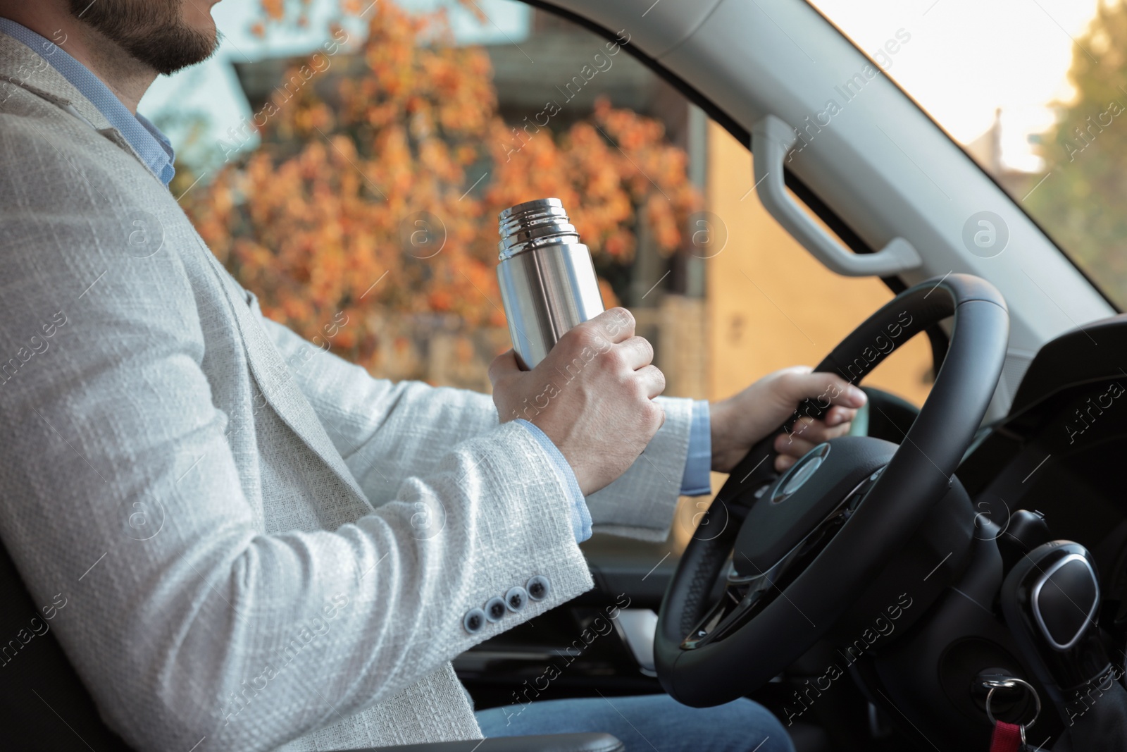 Photo of Man with thermos driving car, closeup view