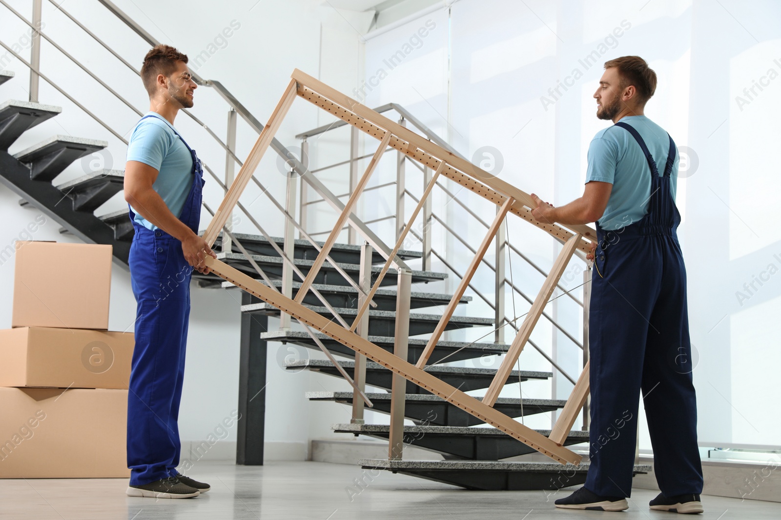 Photo of Professional workers with wooden rack at stairs in office. Moving service