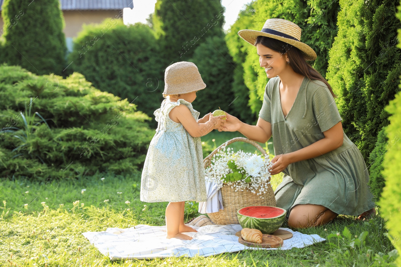 Photo of Mother with her baby daughter having picnic in garden on sunny day