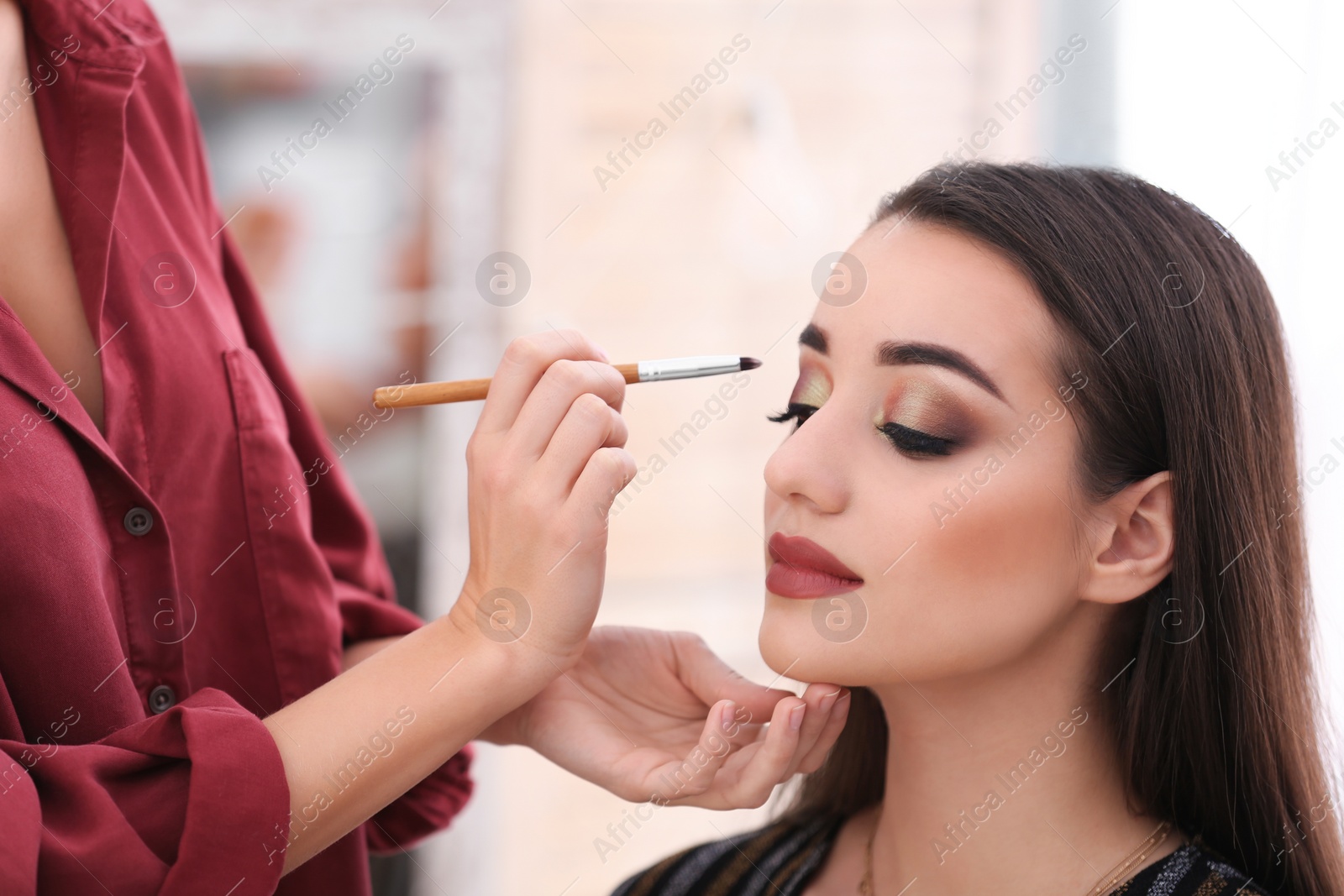 Photo of Professional visage artist applying makeup on woman's face in salon